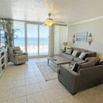 living are with two couches and chair with television and sliding doors overlooking gulf shores beach