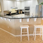 kitchen bar with stools and stainless steel kitchen appliances with white cabinets