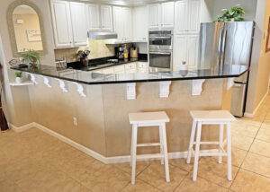 kitchen bar with stools and stainless steel kitchen appliances with white cabinets